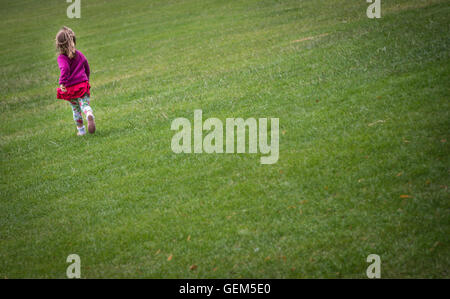 Bambina vestito in rosa polare in esecuzione superiore nel parco in un pomeriggio autunnale Foto Stock