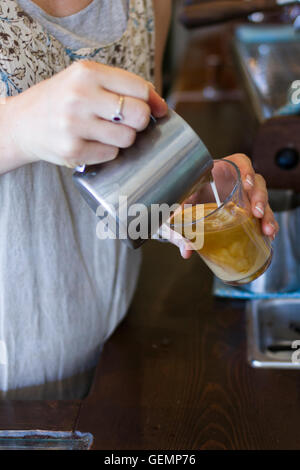 Barista versa latte vaporizzato in un caffè presso l Ammiraglio Cheng Ho café in Abbotsford, Melbourne Australia Foto Stock