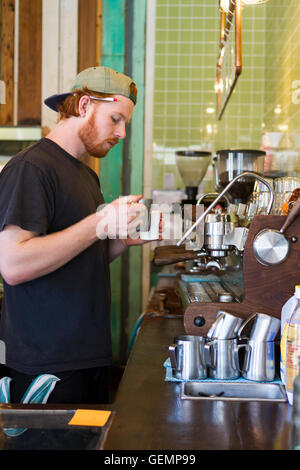 Barista versa latte vaporizzato in un caffè da asporto presso l Ammiraglio Cheng Ho cafe in Abbotsford, Melbourne Australia Foto Stock