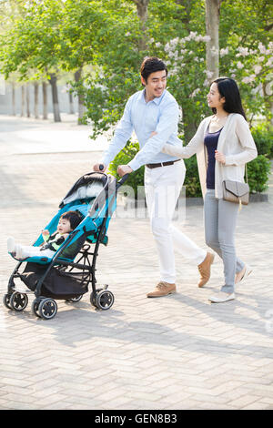 Giovani cinesi giovane facendo una passeggiata con il loro bambino nella PRAM Foto Stock
