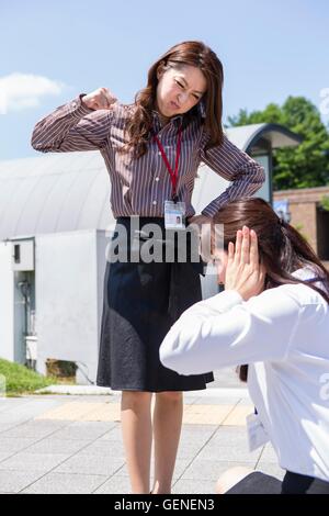 Una donna d'affari essendo arrabbiato e l'altra donna che copre le sue orecchie Foto Stock