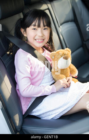 Carino Little Chinese ragazza seduta in auto sedile posteriore Foto Stock