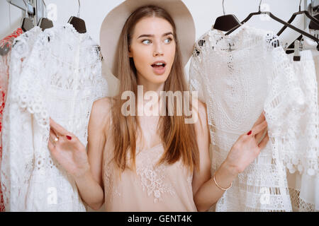 Felice stupiti giovane donna in hat in piedi nel negozio di abbigliamento Foto Stock