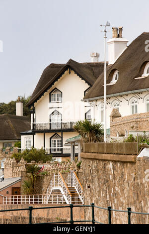 Regno Unito, Inghilterra, Devon, Sidmouth, lungomare con tetto di paglia di case sulla collina di picco strada si affaccia Clifton Beach Foto Stock