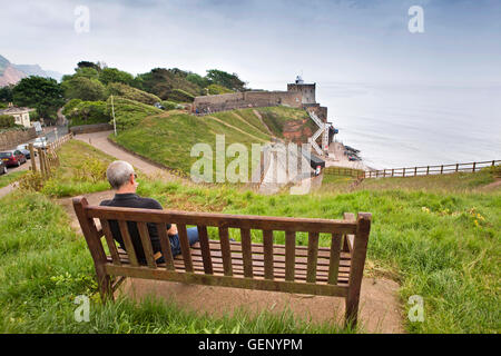 Regno Unito, Inghilterra, Devon, Sidmouth, uomo seduto su un banco di lavoro sopra sopra la scala di Giacobbe e la spiaggia di Torre dell orologio cafe Foto Stock