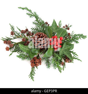 Inverno allestimento floreale con agrifoglio e bacche rosse, edera, pigne, cedro cipressi e abeti bianchi su sfondo bianco. Foto Stock