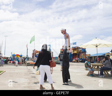 I turisti con un stilt man a Auckland Festival anniversario Foto Stock