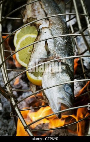 Pesce in un fish grill cesto su un barbecue. Foto Stock