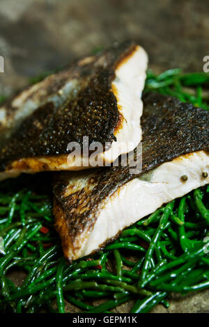 Close up di grigliate di pesce Filetti con pelle croccante su un letto di samphire. Foto Stock