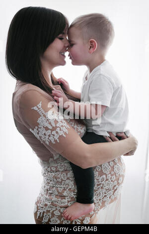 Una donna incinta mentre tiene il suo giovane figlio nelle sue braccia. Foto Stock