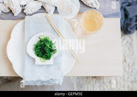 Un tavolo basso prevista per un pasto in una stanza illuminata con candele e decorate per una celebrazione. Foto Stock