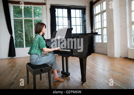 Giovane donna giocando su un pianoforte a coda in una prova studio. Foto Stock