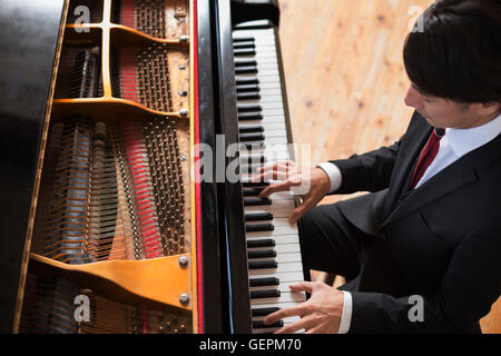 Giovane uomo giocando su un pianoforte a coda in una prova studio. Foto Stock