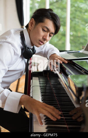 Giovane uomo giocando su un pianoforte a coda in una prova studio. Foto Stock