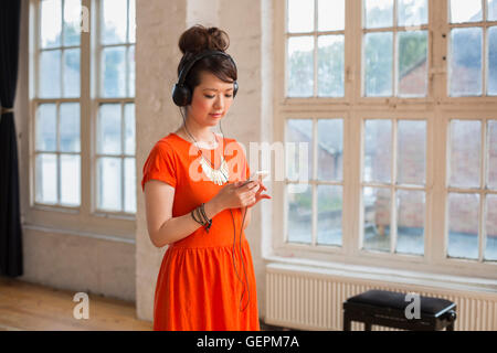 Giovane donna che indossa le cuffie, in piedi in una prova studio, l'ascolto di musica. Foto Stock