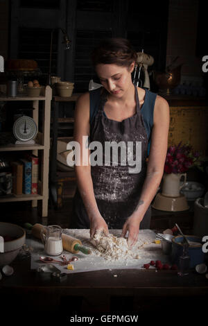 Il giorno di San Valentino la cottura, donna in piedi in una cucina che prepara la pasta per biscotti. Foto Stock