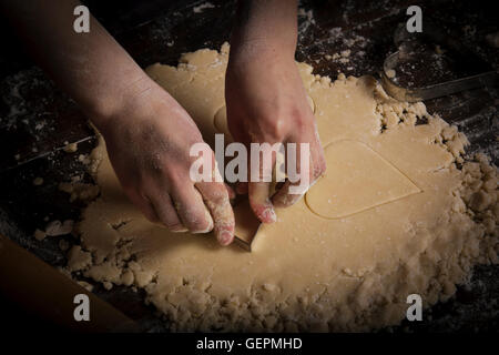 Il giorno di San Valentino la cottura, donna taglio a forma di cuore biscotti di pasta. Foto Stock