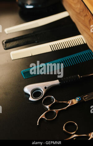 Una fila di pettini per capelli e capelli taglienti forbici da taglio. Foto Stock