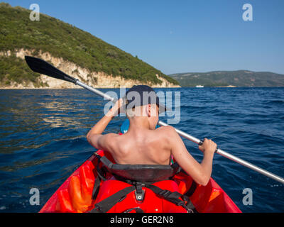 Un giovane ragazzo pagaie sua canoa in vacanza in Grecia Foto Stock