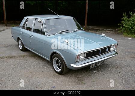 Un Anni Sessanta Ford Cortina MkII saloon sorge sul cemento di fronte a un vecchio capannone coperto Foto Stock