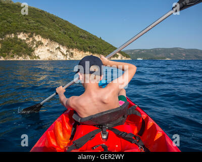 Un giovane ragazzo pagaie sua canoa in vacanza in Grecia Foto Stock