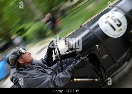 Driver del vintage Bugatti nel periodo meteo ingranaggio su un classico auto da rally, accelerando la distanza dalla linea di partenza Foto Stock