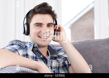 Giovane uomo ascoltare musica su cuffie senza fili Foto Stock
