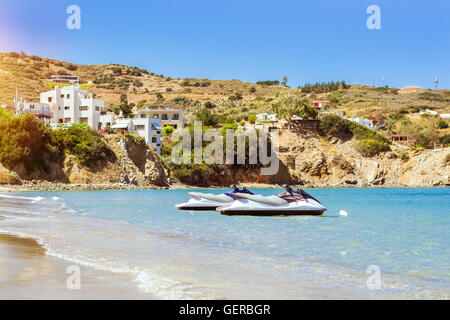 Sunny sandy Livadi spiaggia nella baia del villaggio resort Bali. Acqua scooter parcheggiata vicino alla riva. Vista della costa rocciosa Foto Stock