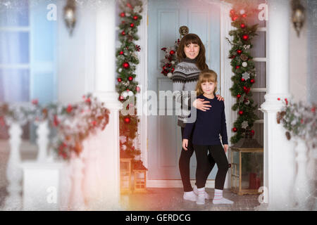 Mamma e figlia in una casa accogliente, decorata l'ingresso alla casa con colori luminosi. In attesa del nuovo anno. Foto di famiglia Foto Stock