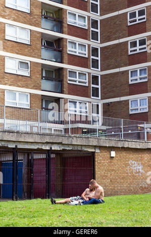 Due uomini seduti sul prato di fronte a un consiglio estate in Bedminster, Bristol Foto Stock