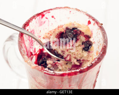 Mug torta con frutti di bosco e cucchiaio, close up Foto Stock