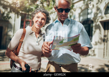 Ritratto di senior coppia turistica in città utilizzando una mappa. Coppia uomo e donna usando la mappa durante la gita. Foto Stock