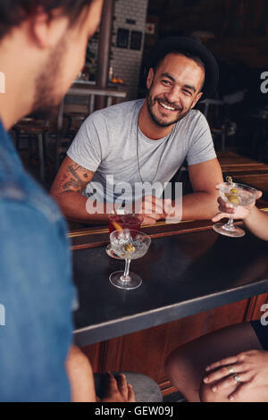 Felice giovane uomo caucasico seduto a un coffee shop con i suoi amici. Giovani amici seduti ad un tavolo del bar con bevande. Foto Stock