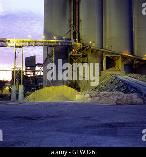 Vista del tramonto di materie prime e di silos a impianto di cemento. Foto Stock