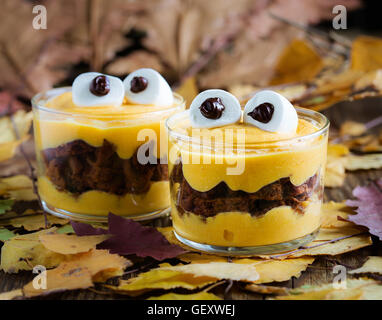 Tratta di Halloween, little monster dessert con biscotti al cioccolato e arancia crema di mascarpone e rabboccato con grandi occhi marshmallow Foto Stock