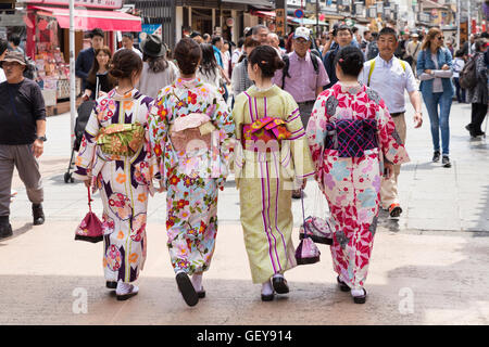 Quattro giovani donne che indossano tradizionali abiti giapponesi passeggiando insieme attraverso le strade laterali intorno al Tempio di Senso-ji, Tokyo Foto Stock