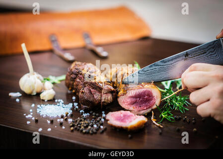 Servire il carving arrosto di maiale rotolo di carne pasto in stile rustico con condimenti Foto Stock