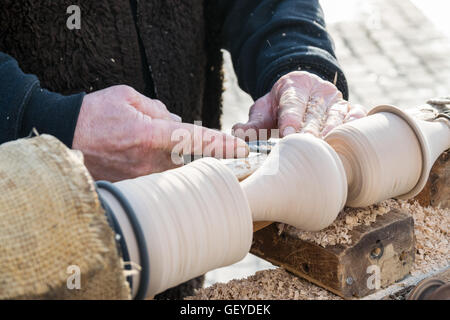 Un artigiano si ritaglia un pezzo di legno utilizzando un vecchio manuale tornio. Foto Stock