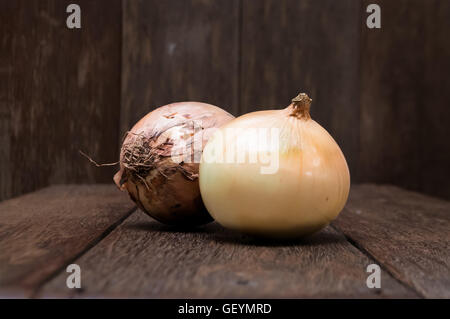 Pelati e non pelati cipolle vintage sulla tavola di legno. La cipolla è un ortaggio più ampiamente coltivato specie del genere Allium. B Foto Stock