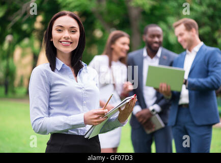 Donna positiva tenendo papers Foto Stock