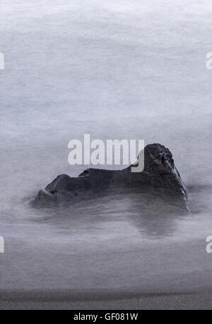 Grande roccia circondato da seta acqua sfocata sulla costa dell'isola di Sao Miguel nelle Azzorre Foto Stock