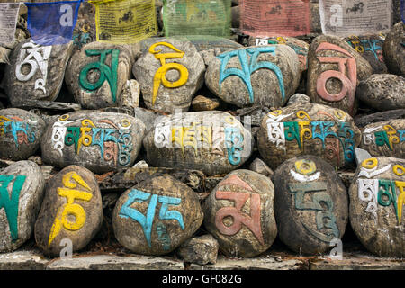 Mani pietre nel villaggio nepalese, buddista antiche pietre scolpite con il sacro mantra religioso scritto in lingua tibetana Foto Stock