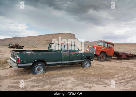 Vecchio pick-up verde d'epoca abbandonato e rimorchio rosso arrugginito in un remoto paesaggio desertico sotto un cielo nuvoloso. Thompson Springs, Utah Foto Stock