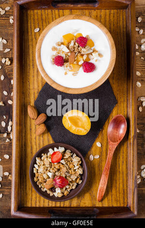 Lo yogurt naturale con muesli e frutta su un vassoio. Colazione sana nozione. Vista superiore Foto Stock