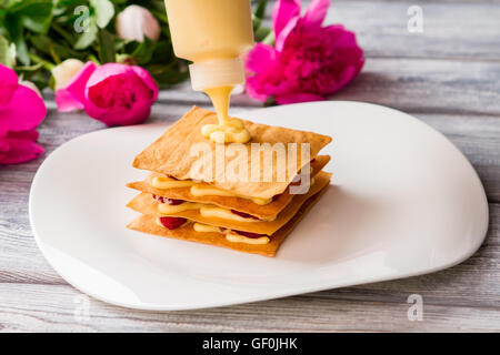 Bottiglia mette la crema su shortcake. Foto Stock