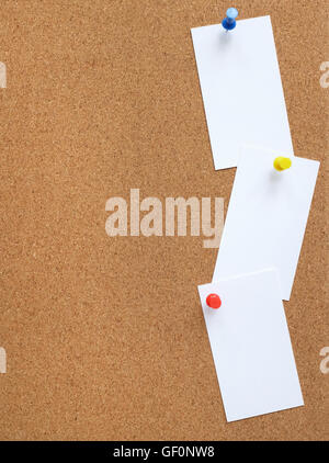 Verticale bacheca di sughero con tre carte bianche imperniata verticalmente verso il basso il lato con il disegno colorato perni Foto Stock