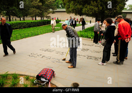 Aprile 26, 2016 Tiantan Park, Pechino Cina. Un anziano uomo Cinese scrittura calligrahy cinese con acqua sul marciapiede. Foto Stock