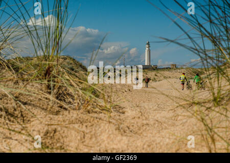 La gente a piedi tra le dune di sabbia verso il faro di Capo Trafalgar, sulla costa dalla piccola località balneare di Los Caños de Foto Stock