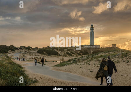 La gente a piedi tra le dune di sabbia verso il faro di Capo Trafalgar, sulla costa dalla piccola località balneare di Los Caños de Foto Stock