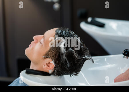 Giovane uomo al parrucchiere di ottenere i suoi capelli lavati Foto Stock